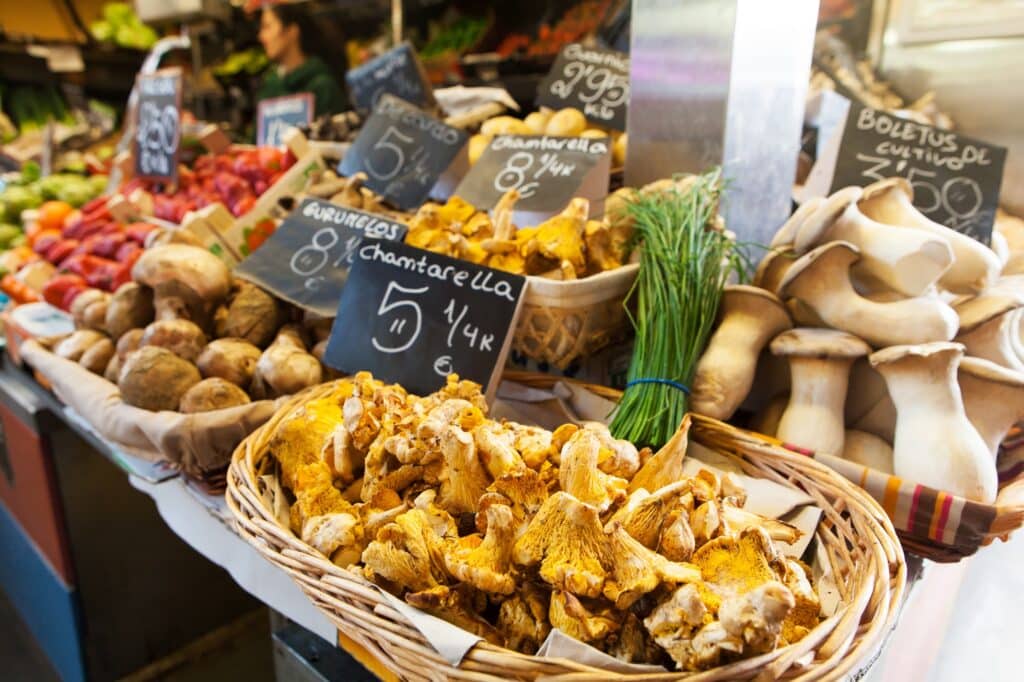Pfifferlinge und andere Pilze und Gemüse in Körben an einem Marktstand