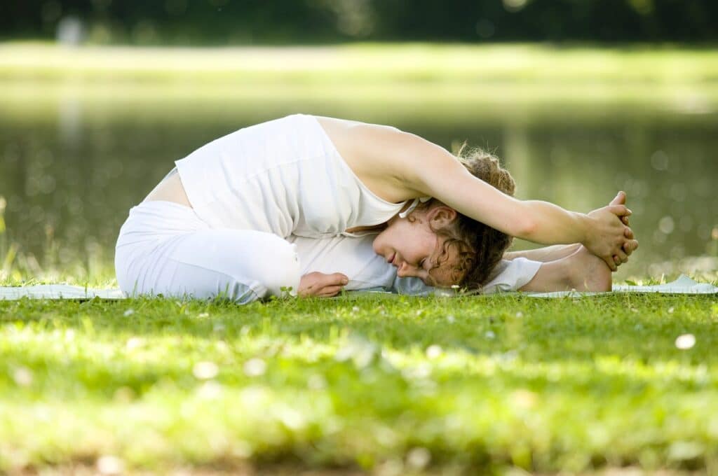 Junge Frau macht Yoga auf grüner Wiese