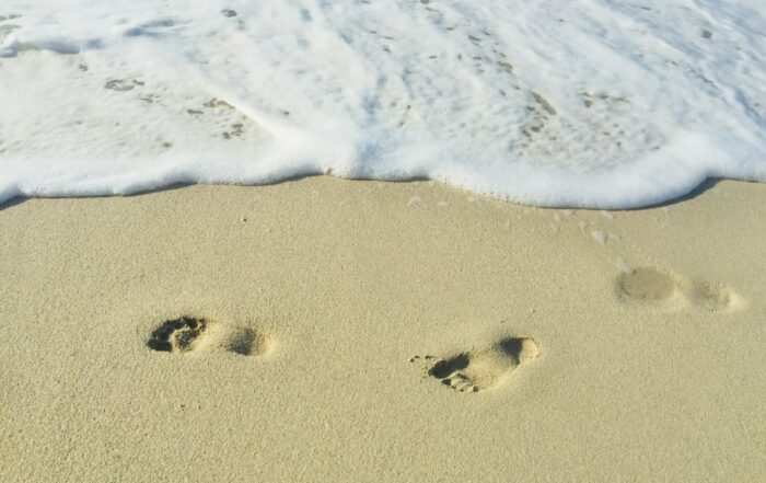 Von Wellen umspülte Fußabdrücke im Sand