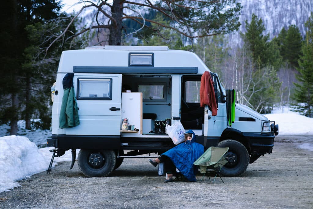 Woman sit next to overlanding 4x4 camper van