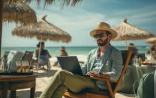 Mann in lässiger Sommerkleidung und Hut mit Laptop am Strand