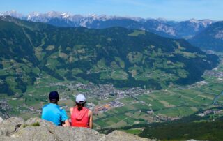 Wanderpaar bei einer Rast mit Aussicht auf das Zillertal