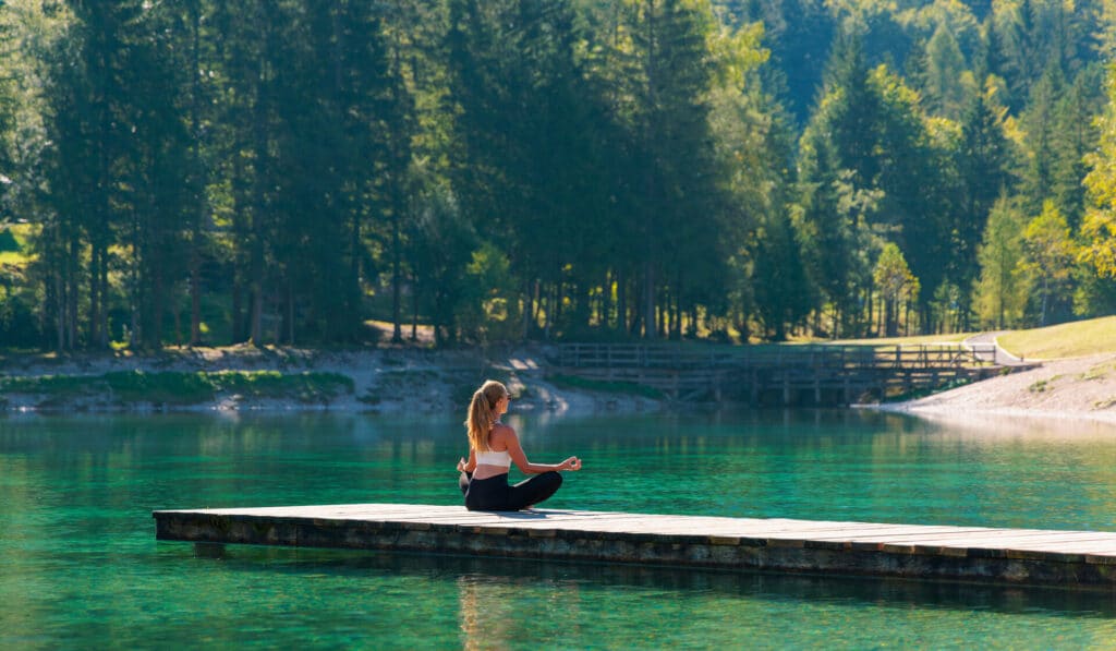 Woman doing yoga on pier on lake- relaxation,zen,healthy lifestyle