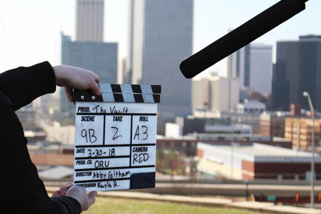 Hände mit Regieklappe vor City Skyline