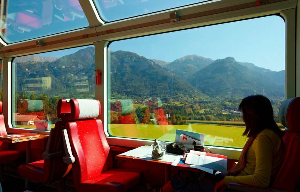 Frau sitzt im Panoramazug in der Schweizer Berglandschaft im Sommer