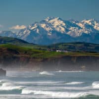 Küste Kantabriens in Norspanien mit den verschneiten Gipfeln der Picos de Europa im Hintergrund