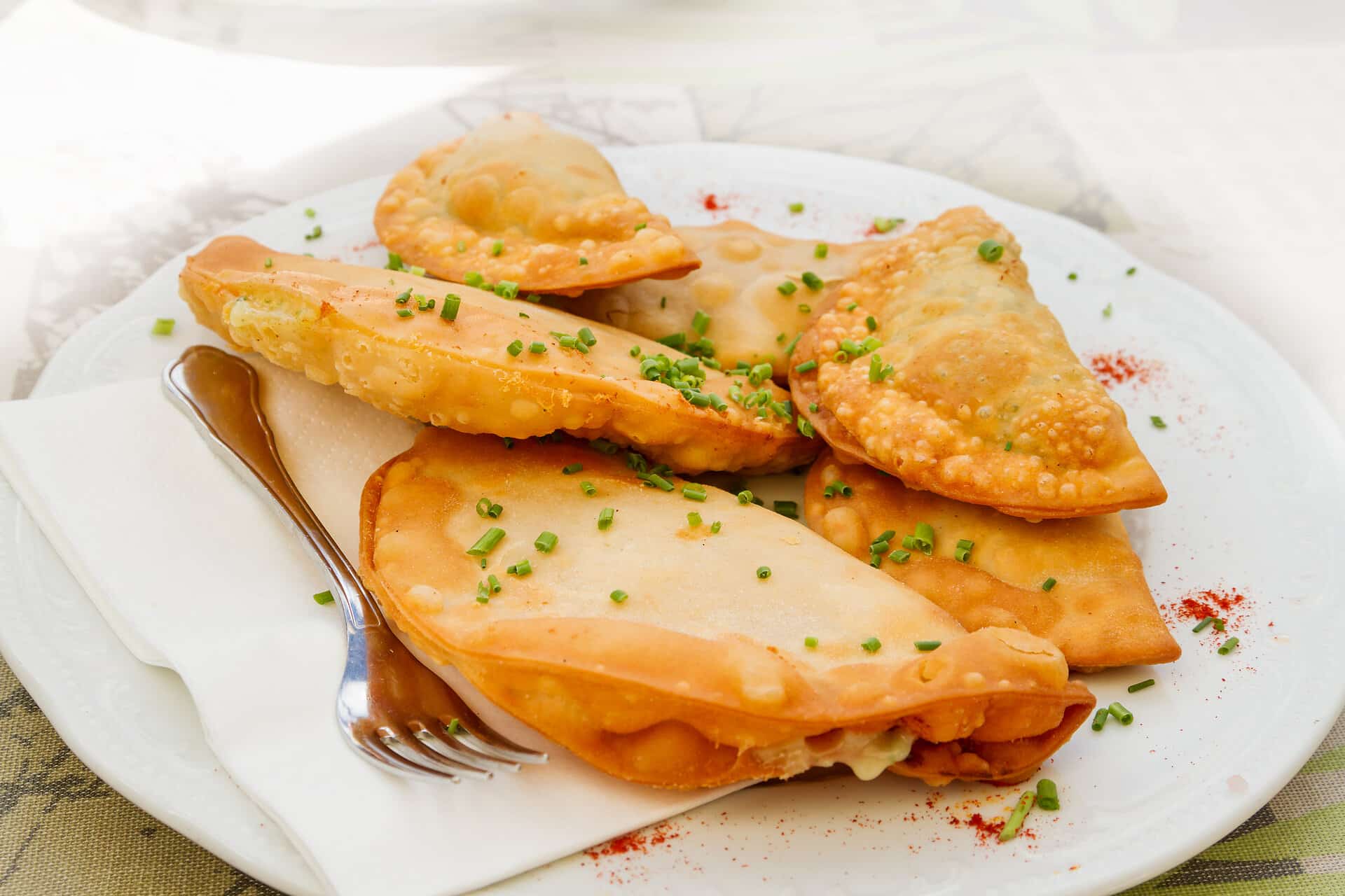 Zillertaler Krapfen mit Schnittlauch bestreut auf einem weißen Teller mit Serviette und Gabel