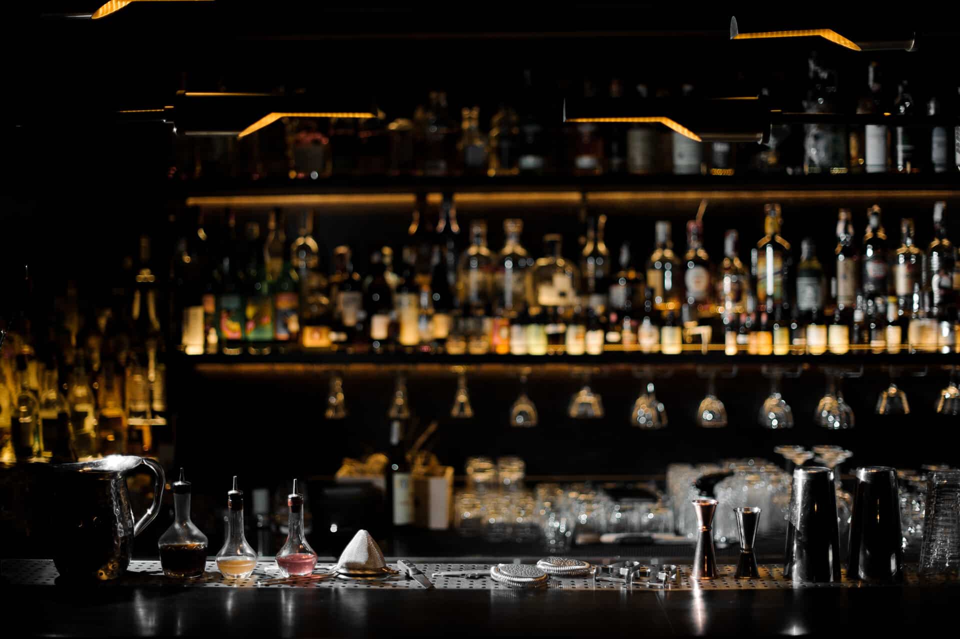 Bartenderequipment auf Tresen vor dunkler beleuchter Bar im Hintergrund