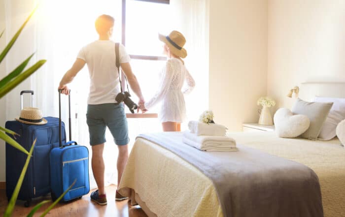 Couple holding hands looking out a window in hotel room