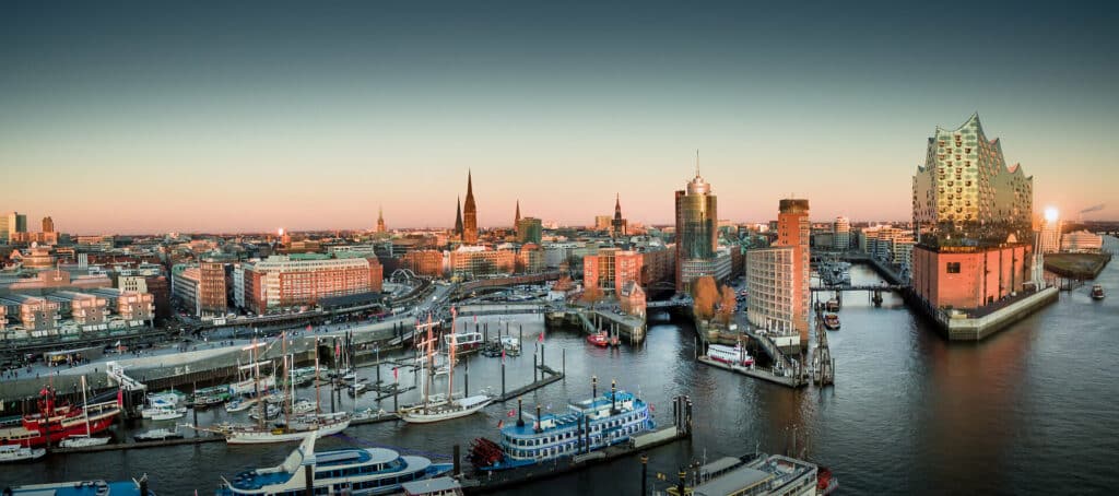 Blick auf Hamburg mit Elbphilharmonie und Speicherstadt bei Sonnenuntergang.