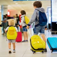 3 Brüder mit Koffern und Rucksäcken an einem Bahnhof oder Flughafen