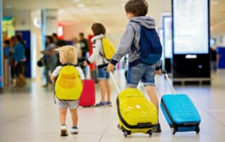 3 Brüder mit Koffern und Rucksäcken an einem Bahnhof oder Flughafen