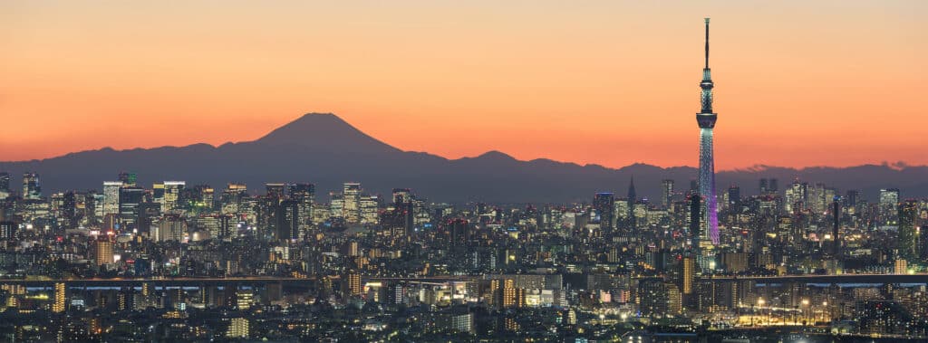 Tokio Skyline bei Sonnenuntergang vor Bergkette mit Mount Fuji