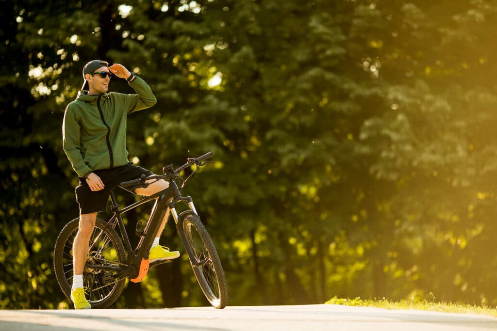 Junger Mann auf einem E-Bike im Sommer im Park