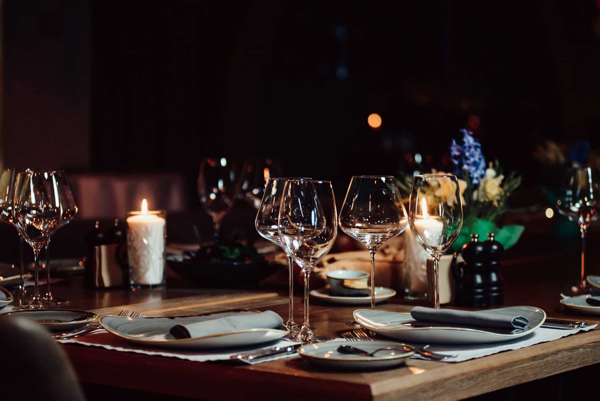 Elegant gedeckter Tisch im Restaurant für 2 mit edlen Gläsern und Kerzen und Blumen