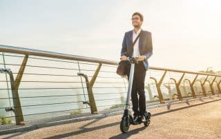 Mann fährt mit dem Scooter über die Brücke